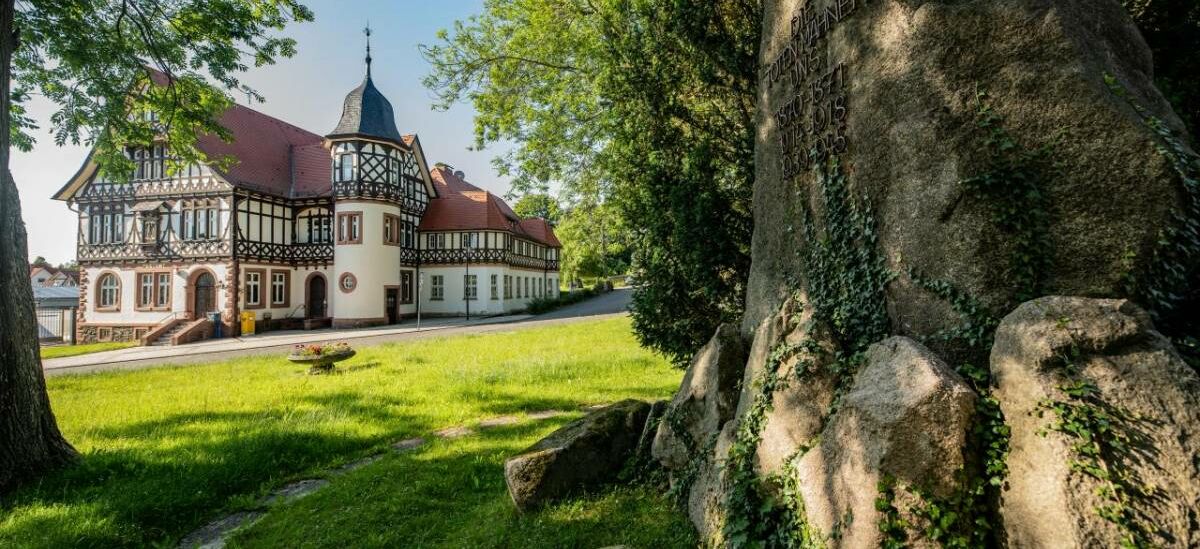 Landschaftsaufnahme mit Historischer Post und Kriegerdenkmal im Vordergrund