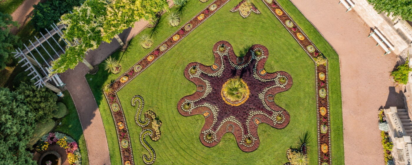 Luftaufnahme bunt bepflanztes Teppichbeet mit Idolino-Brunnen im Schlosspark Altenstein