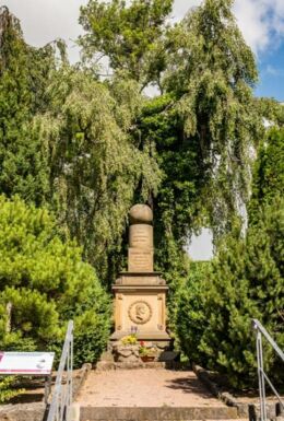 Fröbelgrab Friedhof Schweina mit Portrait von Friedrich Fröbel und den Spielgaben Kugel, Walze und Würfel