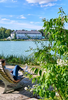 Zwei Frauen entspannen auf einer Bank mit Blick über den Burgsee Bad Salzungen zur Kurklinik