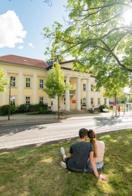 Landschaftsaufnahme mit Pärchen auf Wiese, im Hintergrund Palais Weimar mit Stadt- und Kurbibliothek