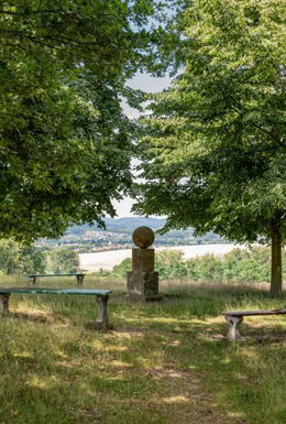 Landschaftsaufnahme mit Fröbelsruh, ursprünglichem Grabstein Fröbels, Sitzbänken und Blick ins Werratal