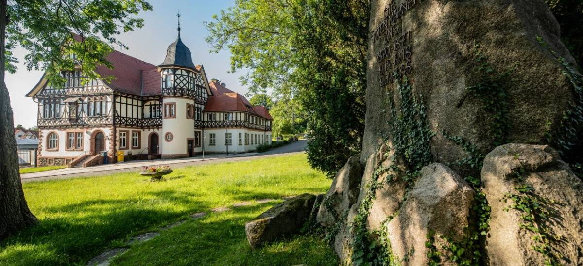 Landschaftsaufnahme mit Historischer Post und Kriegerdenkmal im Vordergrund