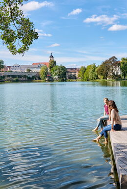 Zwei Frauen lassen am Burgsee Bad Salzungen die Füße im Wasser baumeln...