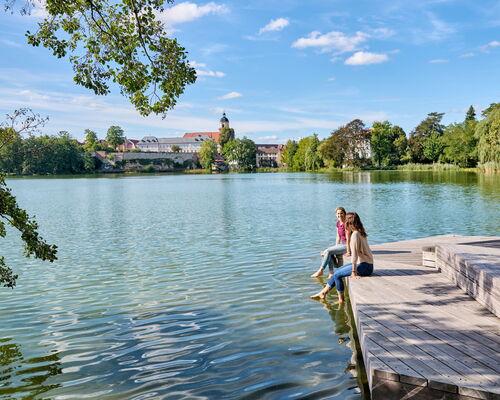 Zwei Frauen lassen am Burgsee Bad Salzungen die Füße im Wasser baumeln...