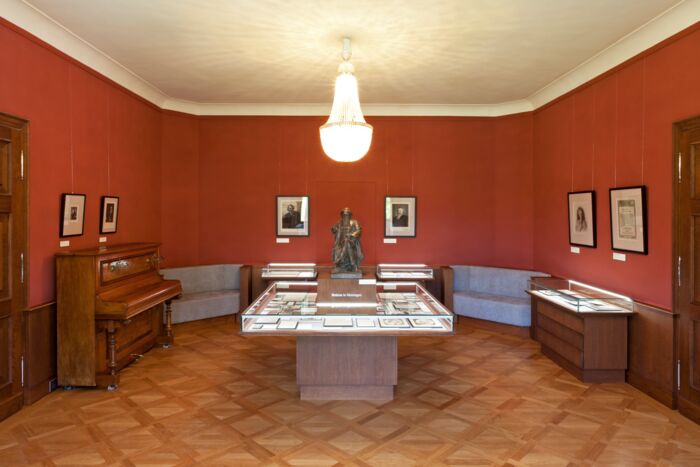 Innenaufnahme Brahms-Gedenkstätte im Schloss Altenstein Innenaufnahme Brahms-Gedenkstätte im Schloss Altenstein mit Brahms-Statue, Klavier, Kronleuchter und Ausstellungsvitrinen