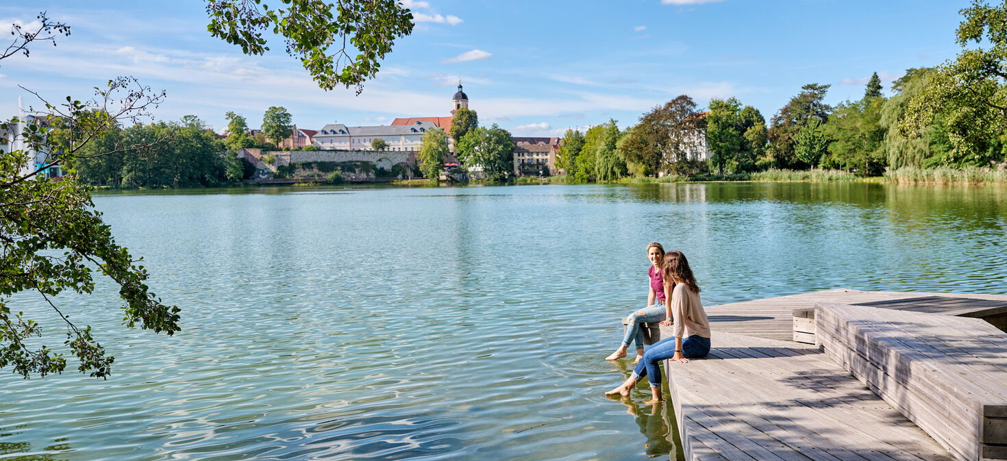 Zwei Frauen lassen am Burgsee Bad Salzungen die Füße im Wasser baumeln...