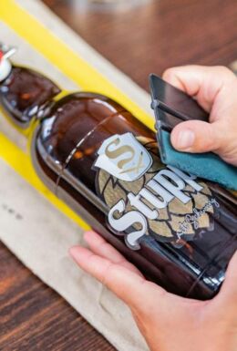 Beklebung einer abgefüllten Flasche Stupps Bier mit Logo