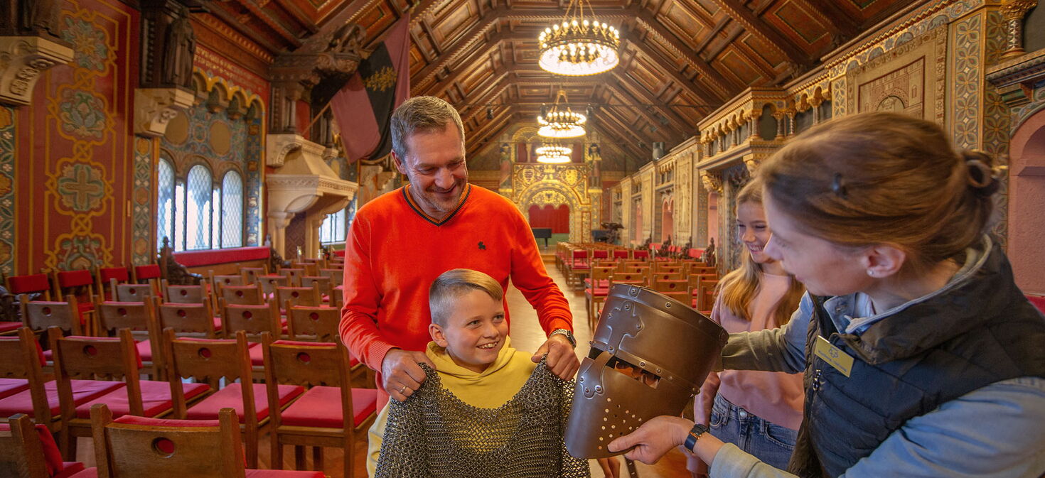 Während einer Familienführung probiert ein Junge eine Rüstung im Festsaal der Wartburg.