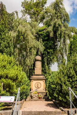 Fröbelgrab Friedhof Schweina mit Portrait von Friedrich Fröbel und den Spielgaben Kugel, Walze und Würfel