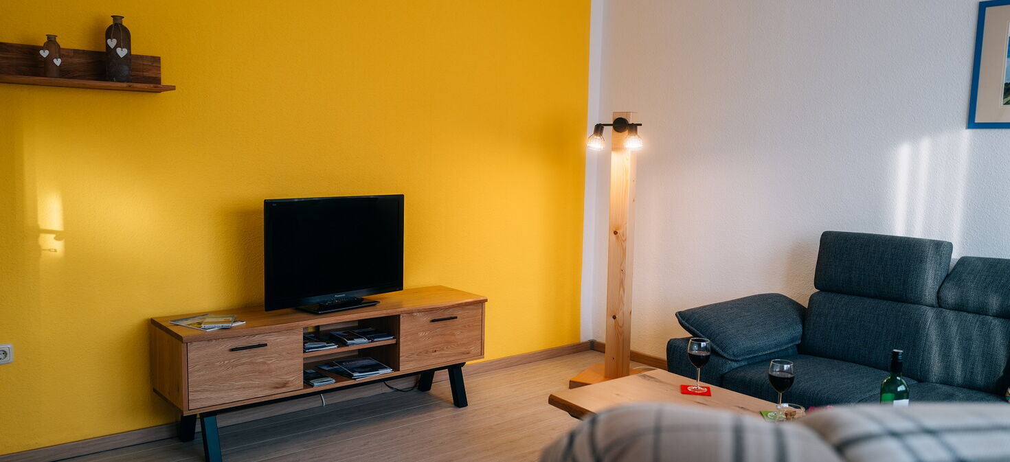 Innenaufnahme Wohnzimmer mit Sessel, Sofa und TV-Bank