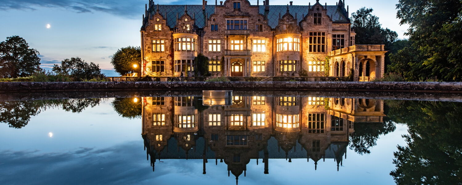Abendaufnahme beleuchtetes Schloss Altenstein mit Wasserspiegelung