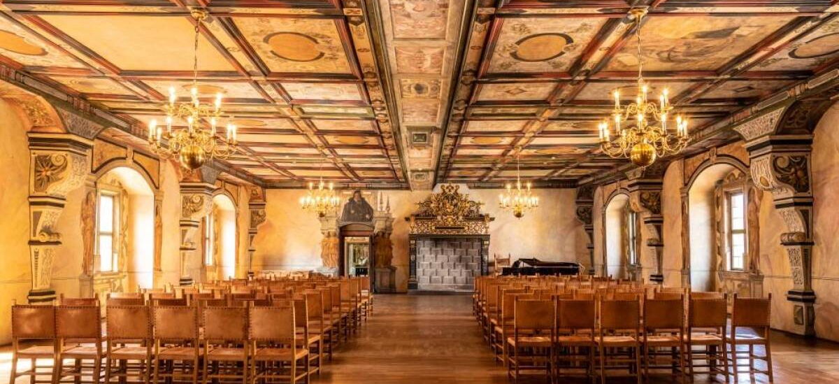 Innenaufnahme Saal im Schloss Wilhelmsburg mit Stühlen, Kronleuchtern und Wandverzierungen