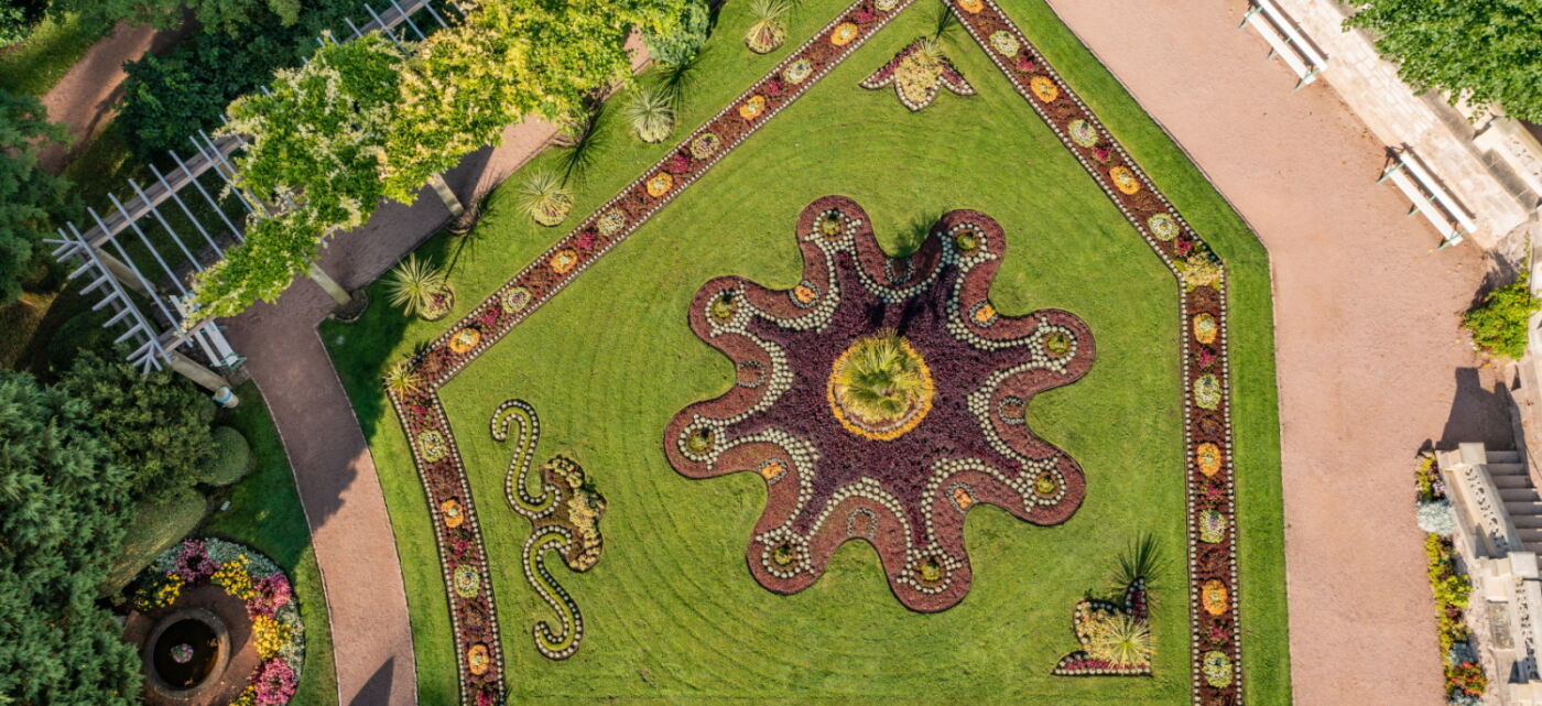 Luftaufnahme bunt bepflanztes Teppichbeet mit Idolino-Brunnen im Schlosspark Altenstein