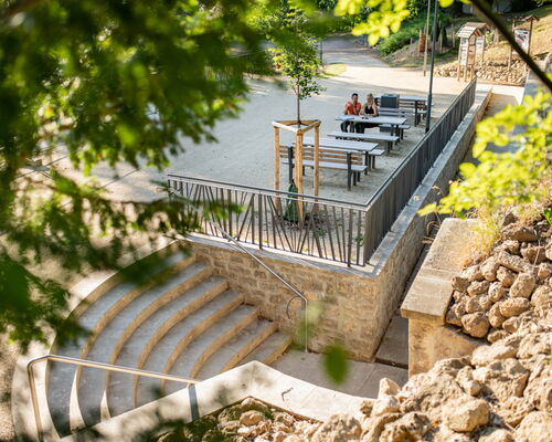 Treppe zum Höhleneingang, Sitzbänke und -tische und Wege im Hintergrund