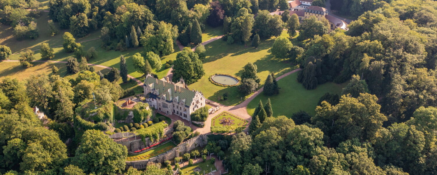 Luftaufnahme Innenpark Schloss & Park Altenstein mit Eingangsbereich, Schloss und Beetanlagen, umgeben von Wald und Natur